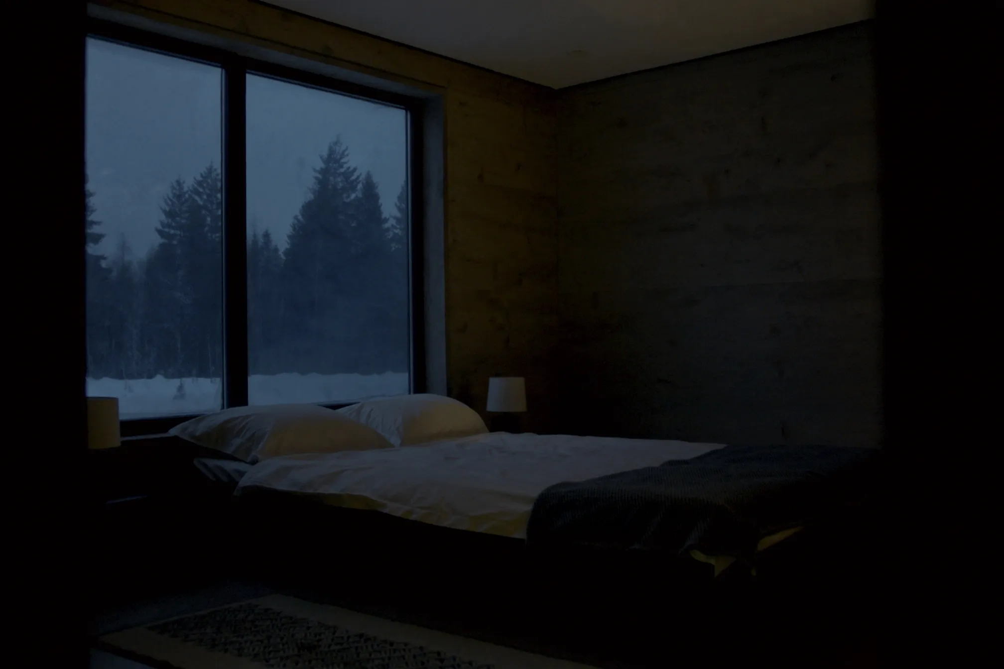A lodge bedroom with a window onto snow-covered forest at dusk