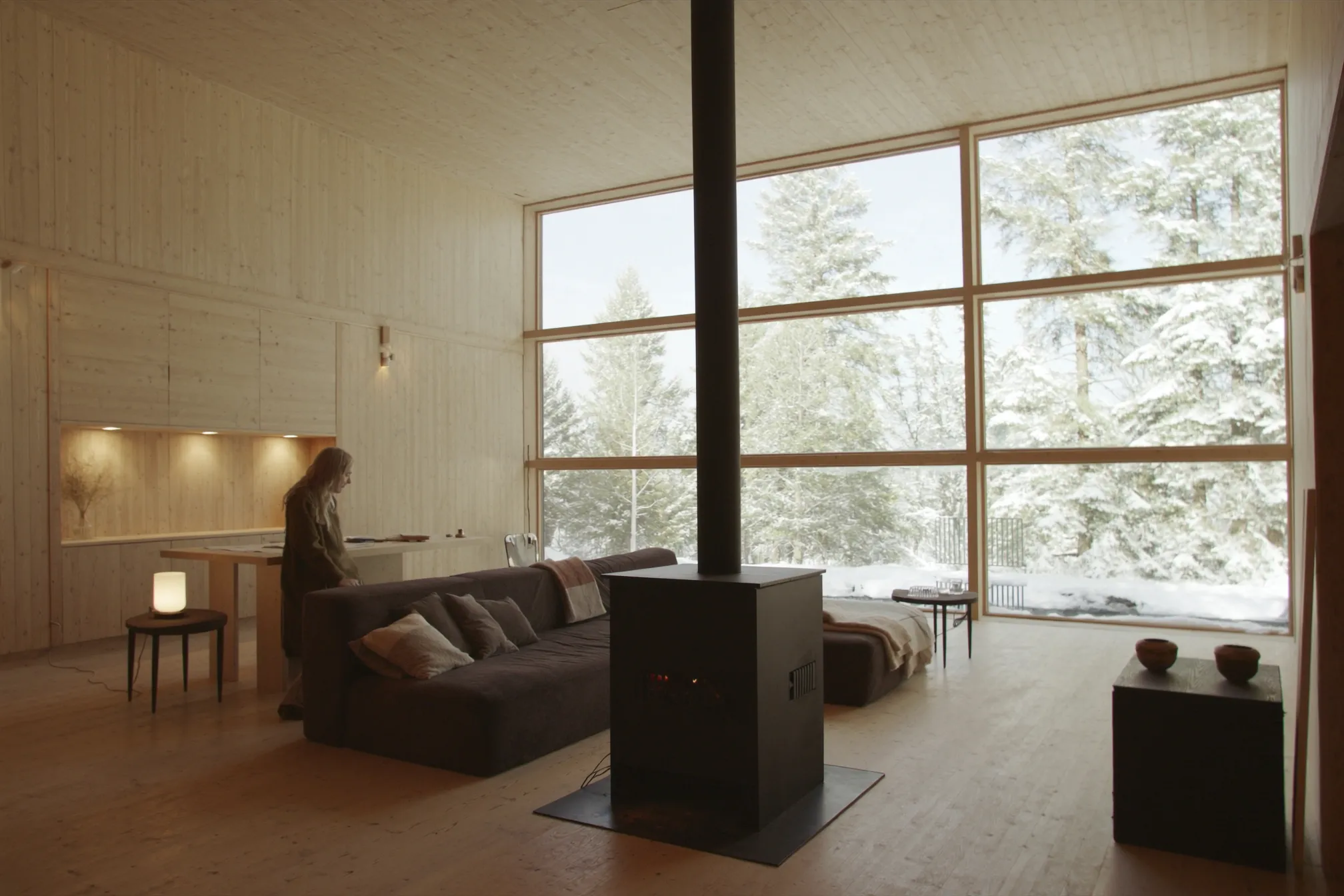 The lodge living room in warm evening light, a large window onto snow