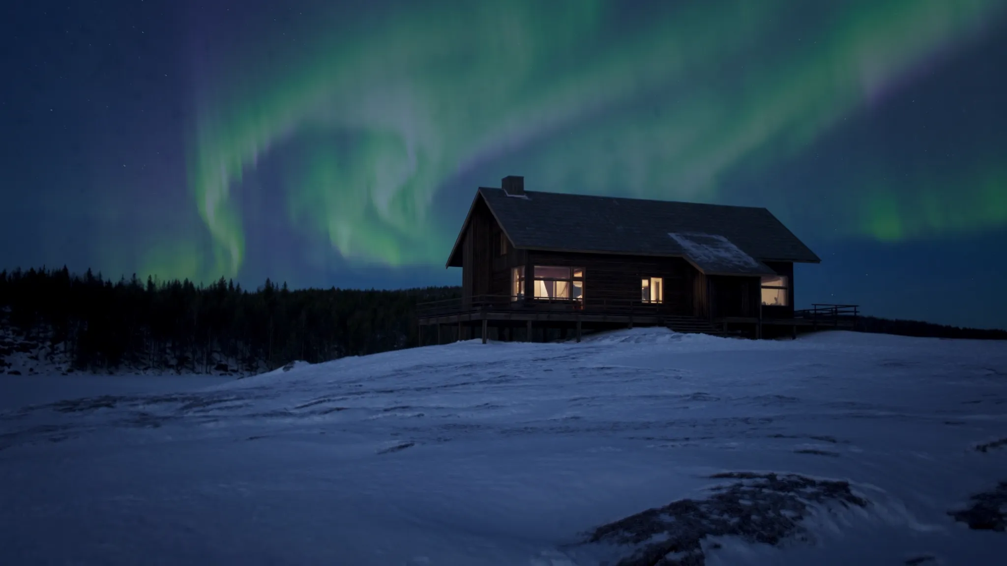 The lodge above the frozen lake under a faint aurora, light in its windows